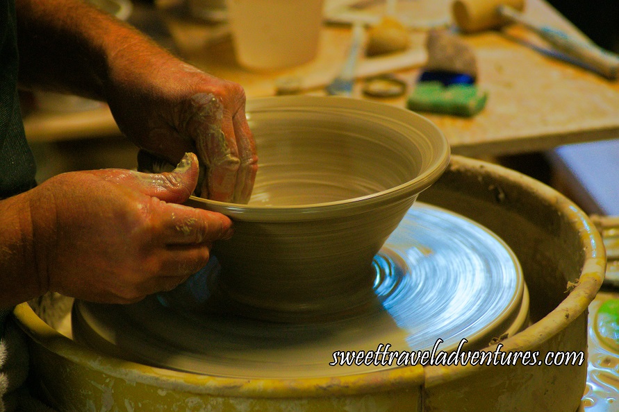 Hands Smoothing Out the Edge of a Large Bowl on a Pottery Wheel Inside a Plastic Container