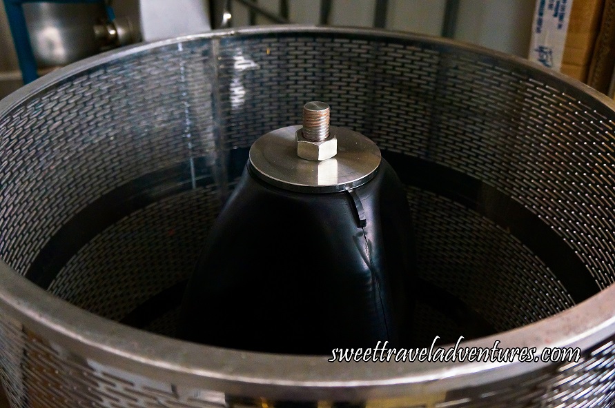 A Machine With a Silver Round Container With Basket Like Weaving Design and a Black Press in the Middle With a Silver Knob on Top