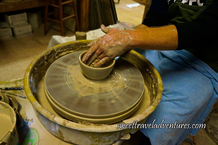 A Hand Smoothing Out a Small Bowl on a Pottery Wheel in a Plastic Bowl With Excess Clay