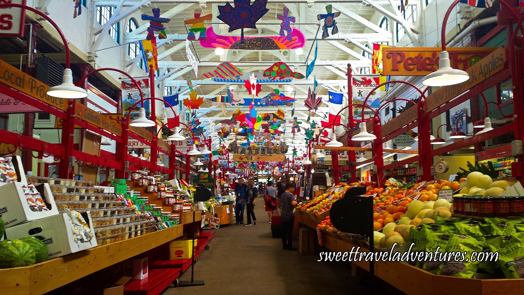 Red Stalls With White Lamps Hanging Down With Fresh Produce on the Right and Packaged Foods on the Left and Colourful Mobiles Hanging From the Rafters
