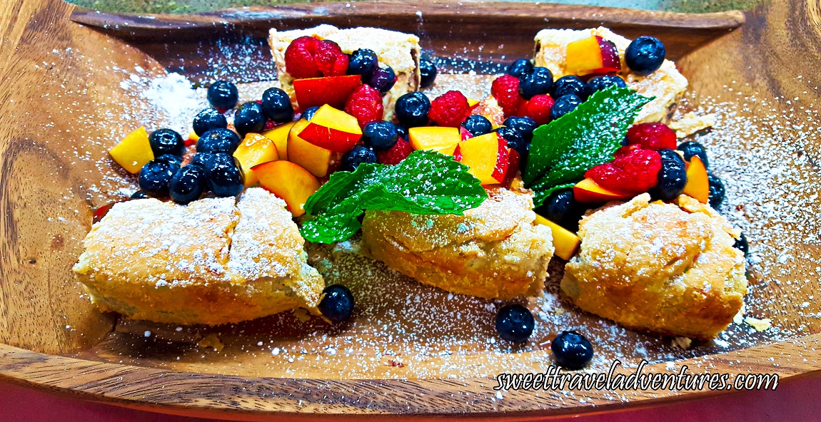 Tarts on a Wooden Tray and Topped With Fresh Peaches, Blueberries, and Raspberries, as well as a Couple Mint Leaves, Drizzled With Honey, and Sprinkled With Icing Sugar