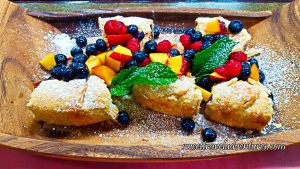 Tarts on a Wooden Tray and Topped With Fresh Peaches, Blueberries, and Raspberries, as well as a Couple Mint Leaves, Drizzled With Honey, and Sprinkled With Icing Sugar