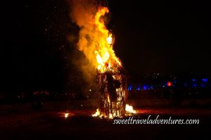 A Wooden Structure Burning at Night With Large Flames and Smoke on the Upper Portion and Some Sparks