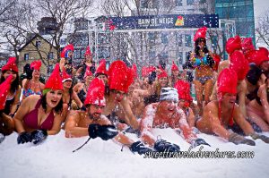 People in Their Bathing Suits Wearing Giant Red Rooster Hats Lying Down in the Snow and a Few People Standing Up Behind